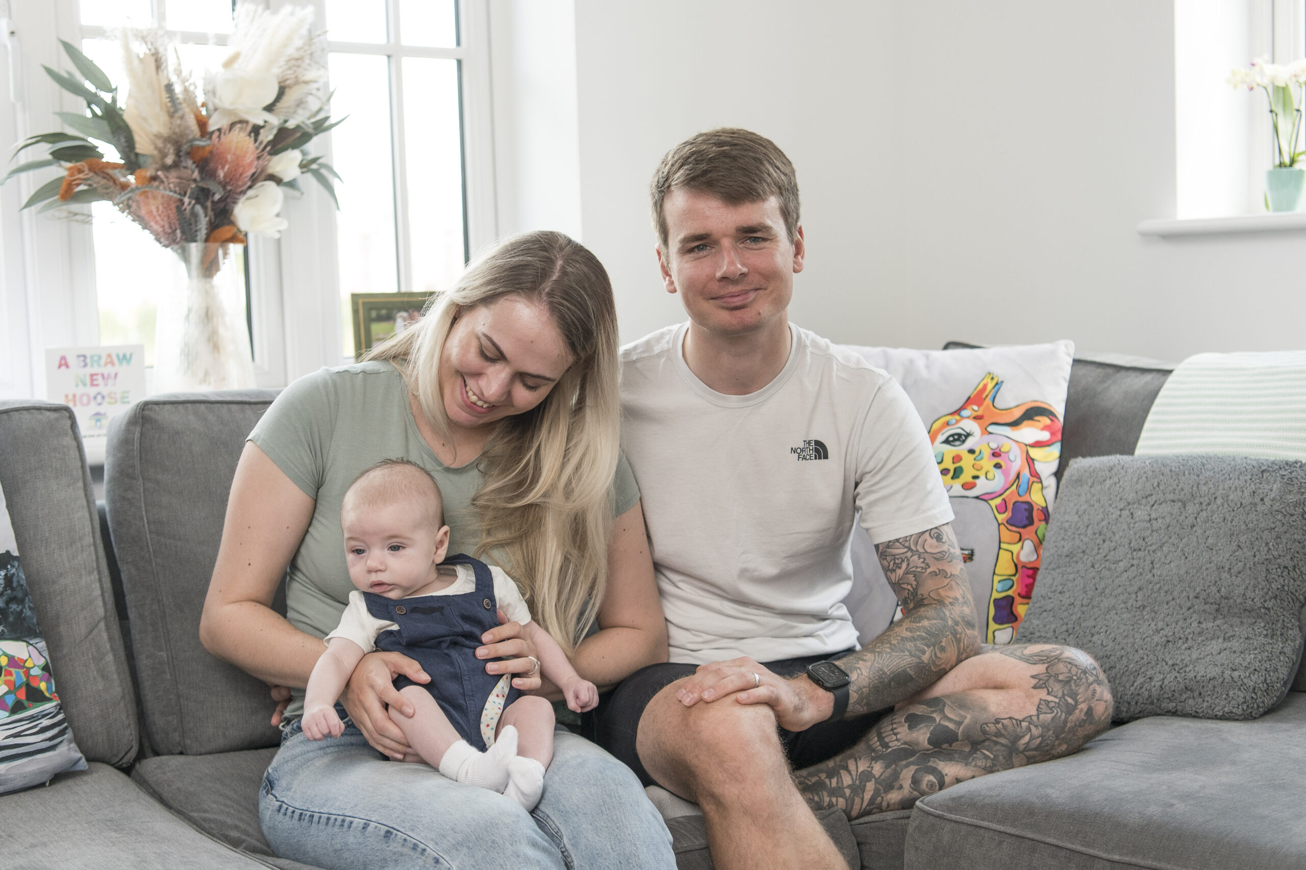 Vikki and Mitch on their sofa with their baby