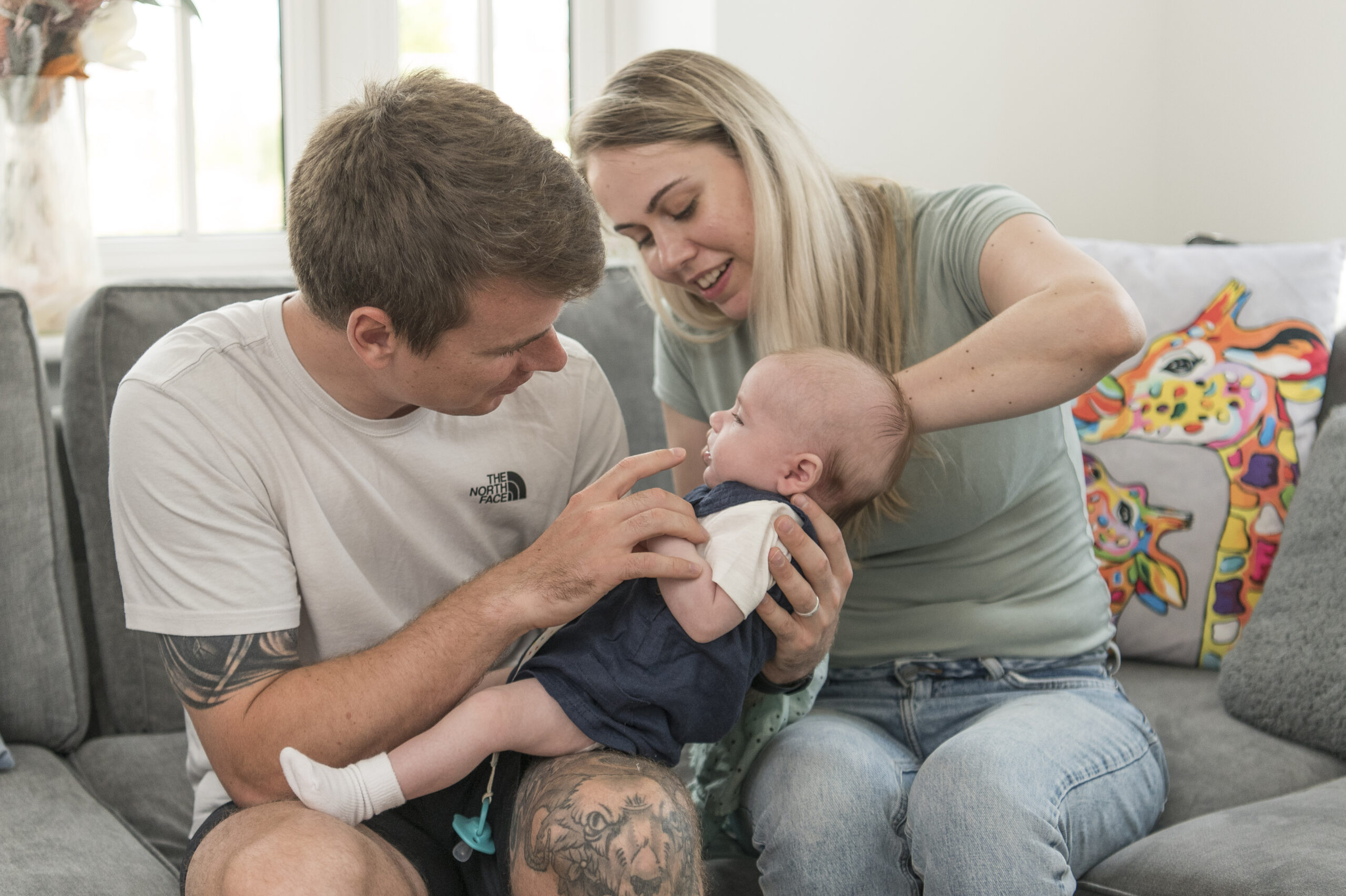 Mitch and Vikki playing with their baby on the sofa