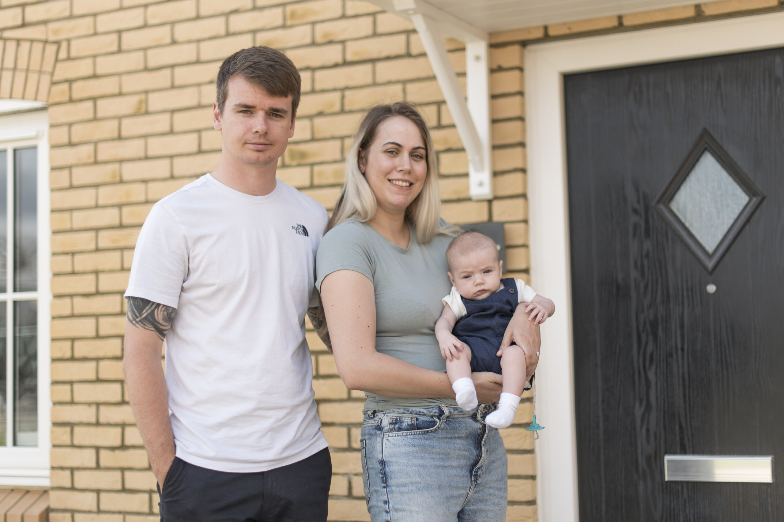Mitch and Vikki holding their baby outside their home