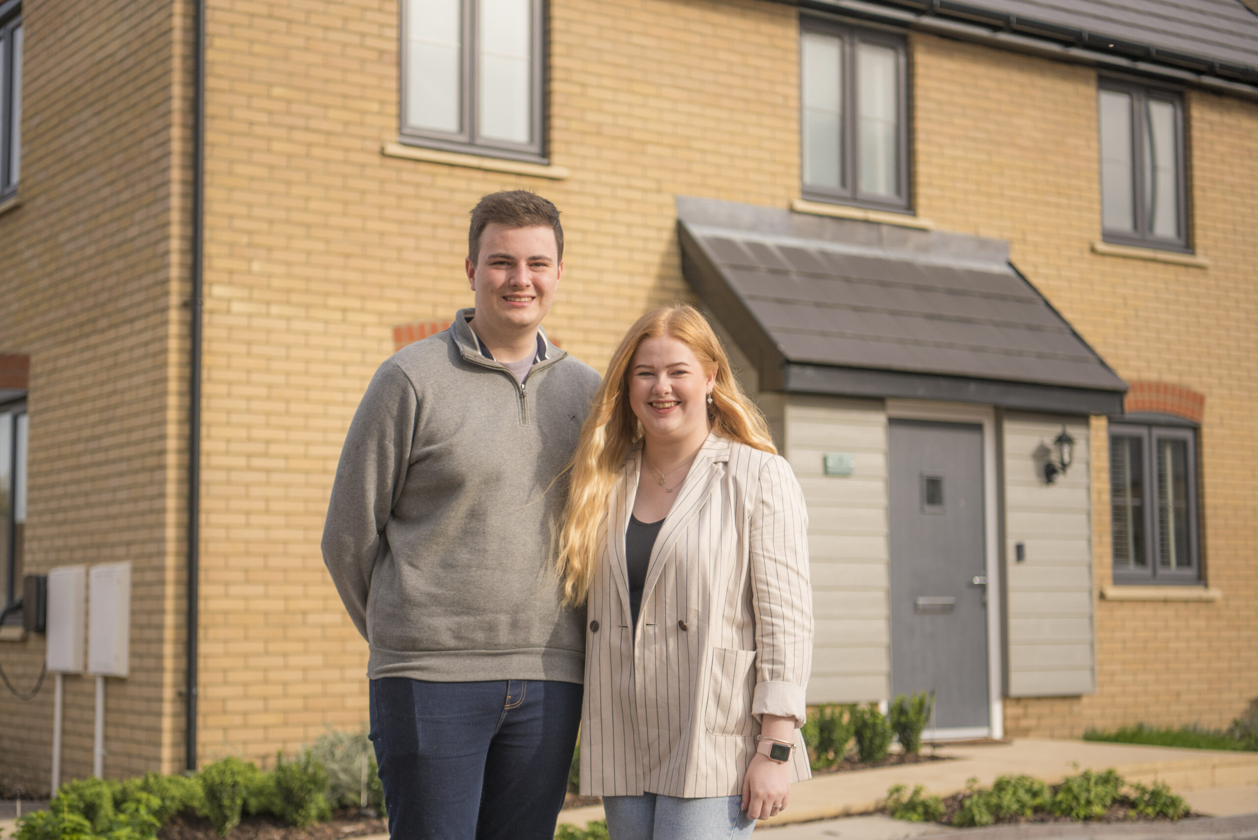 Sam and Emma standing outside their house