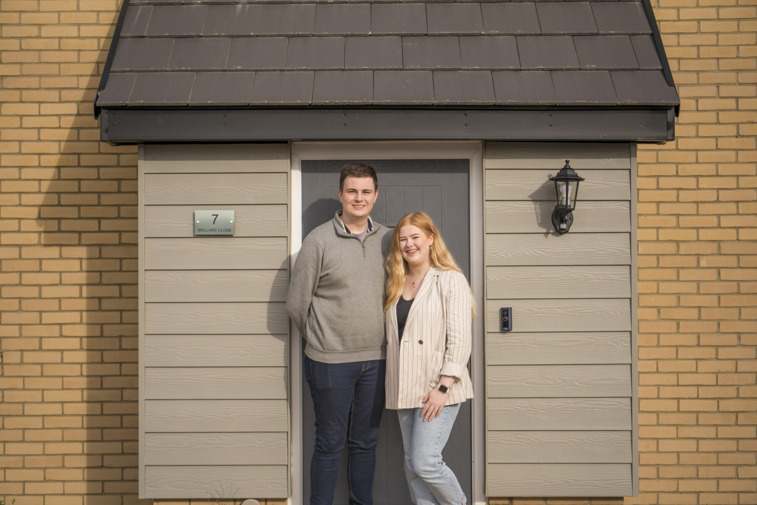 Sam and Emma at the front door of their home