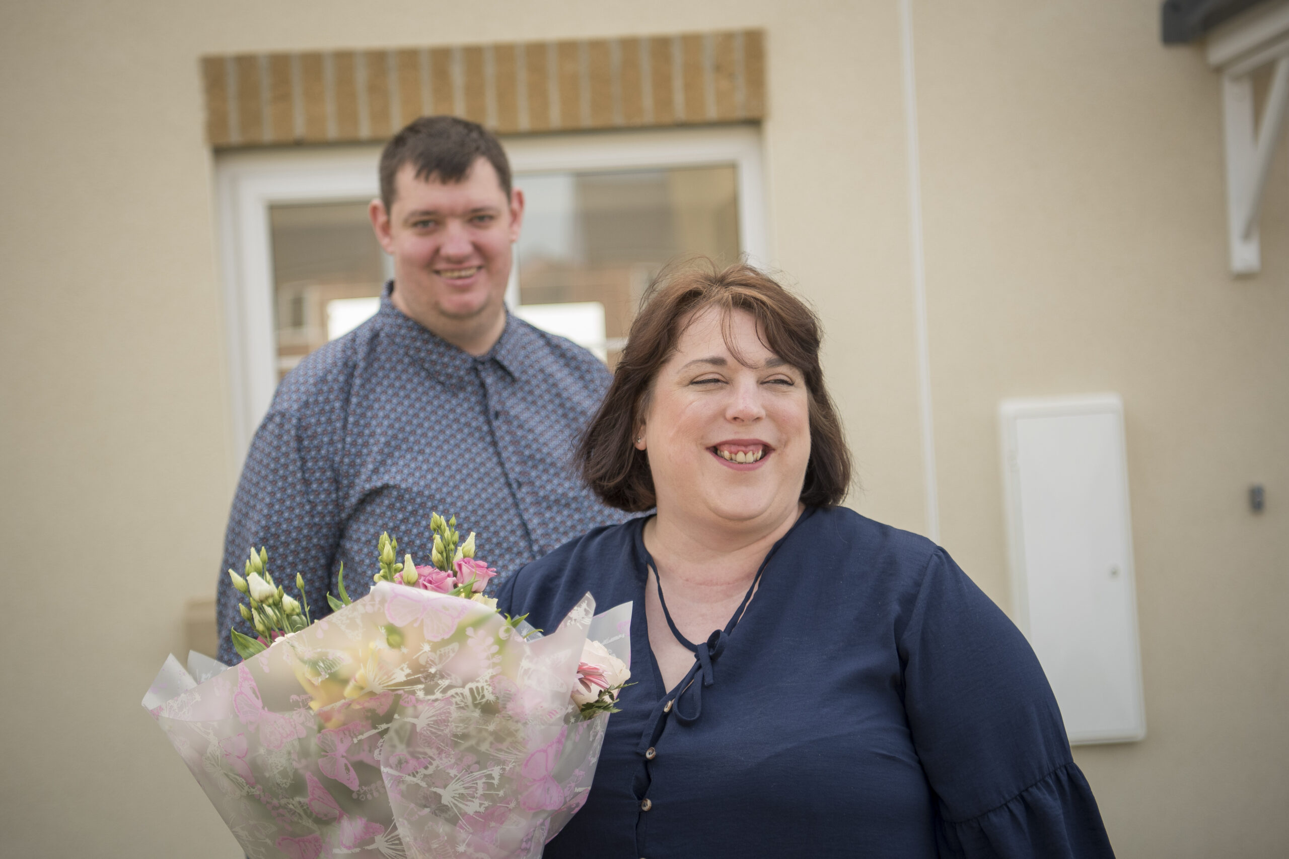 Lewis and Dee indoors, Dee holding a bouquet of flowers