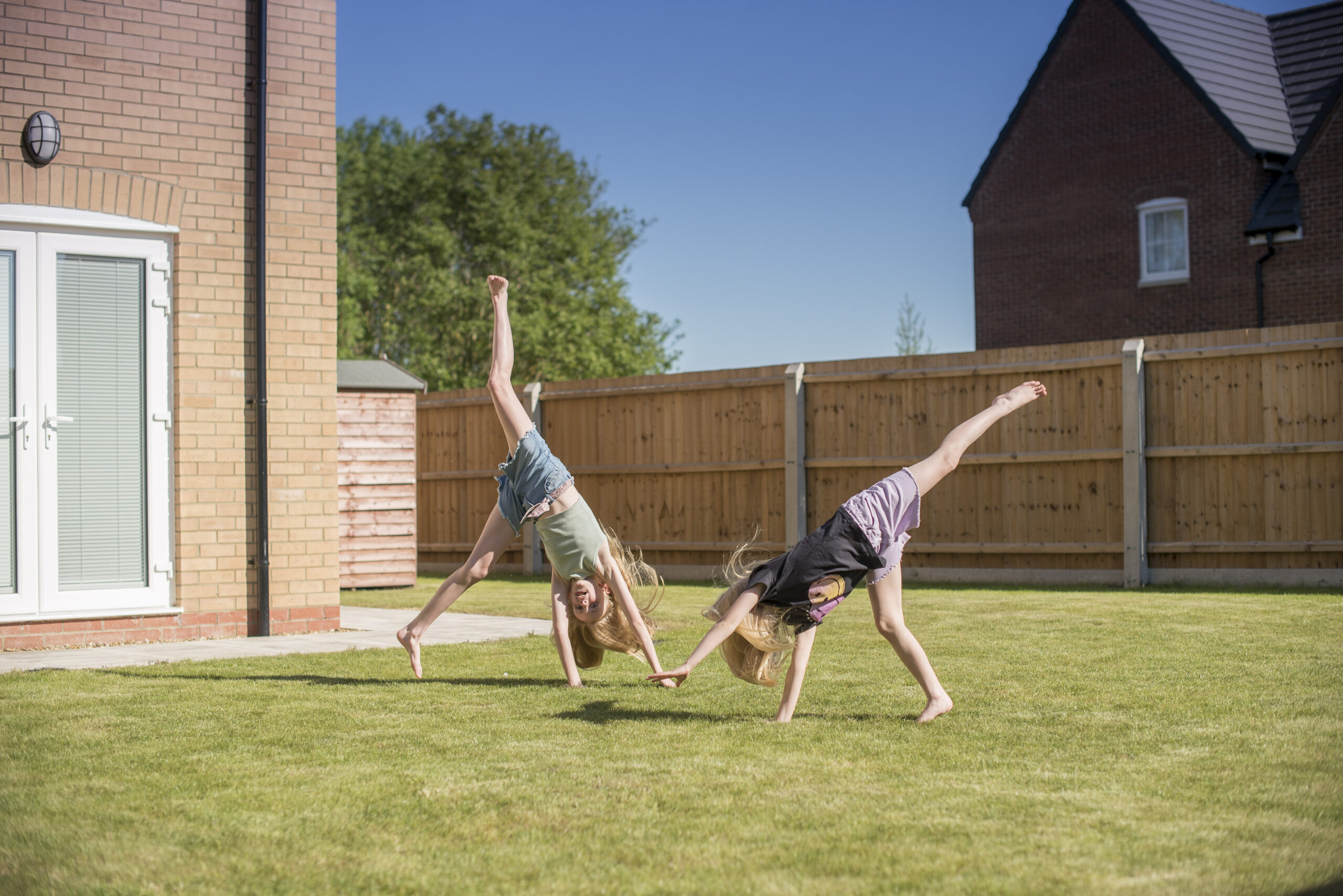 Children doing cartwheels on the garden lawn