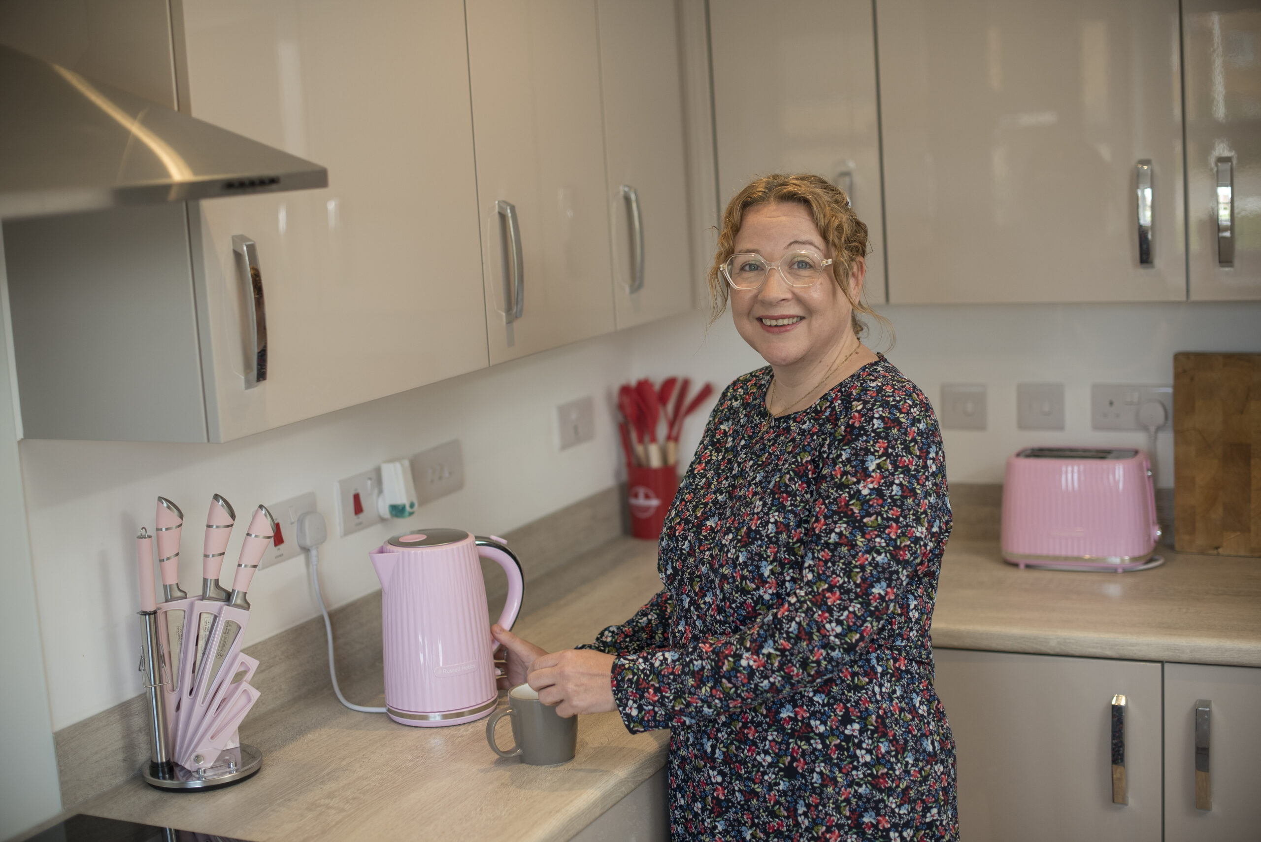 Katie in her kitchen with a pink kettle and toaster