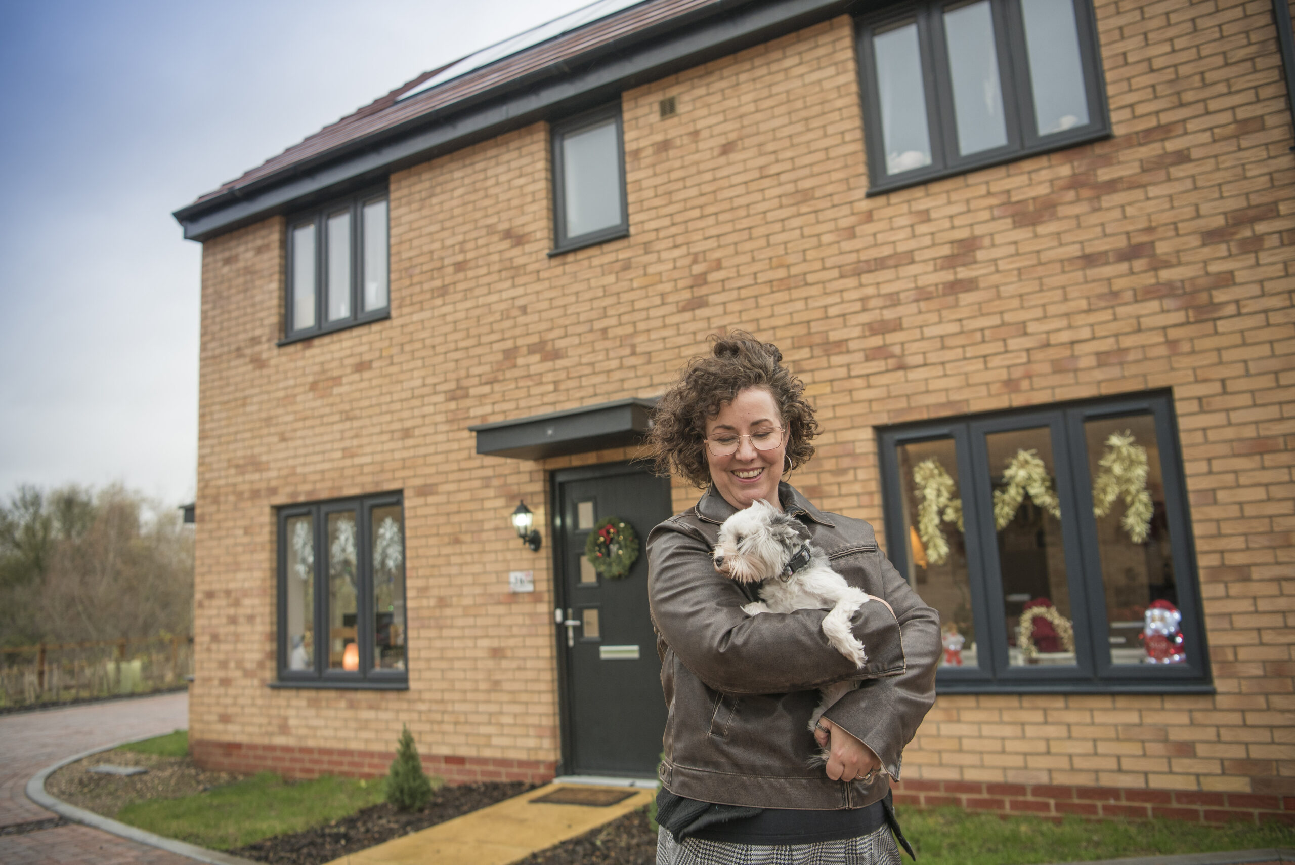 Lisa holding a small dog outside her front door